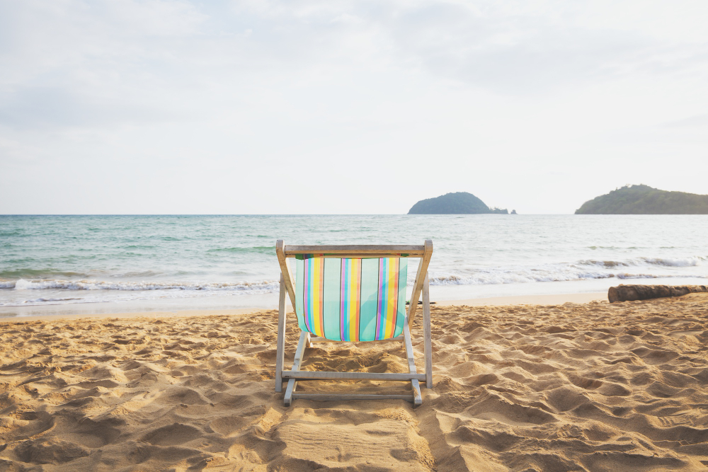 Foto ambiente de uma cadeira de praia na areia, à beira mar