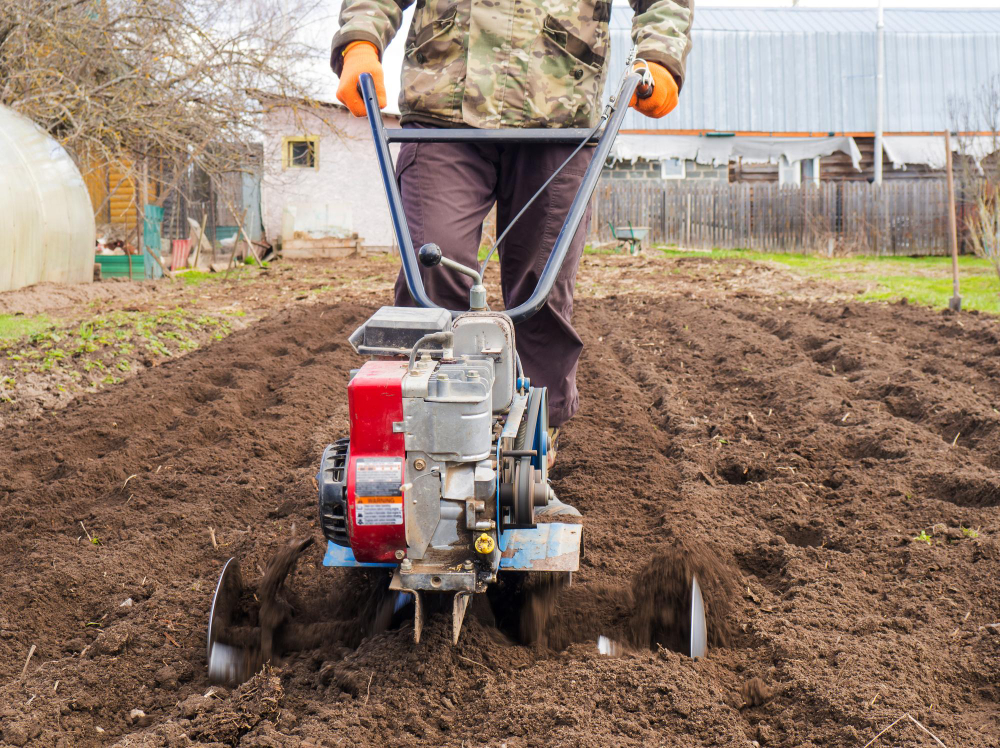 Foto um homem trabalha a terra no jardim com um cultivador prepara o solo para semear