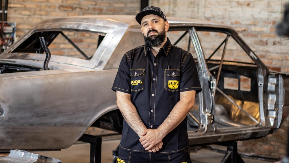 Willian Giacomin, o especialista entrevistado na frente de um carro em processo de restauração na oficina