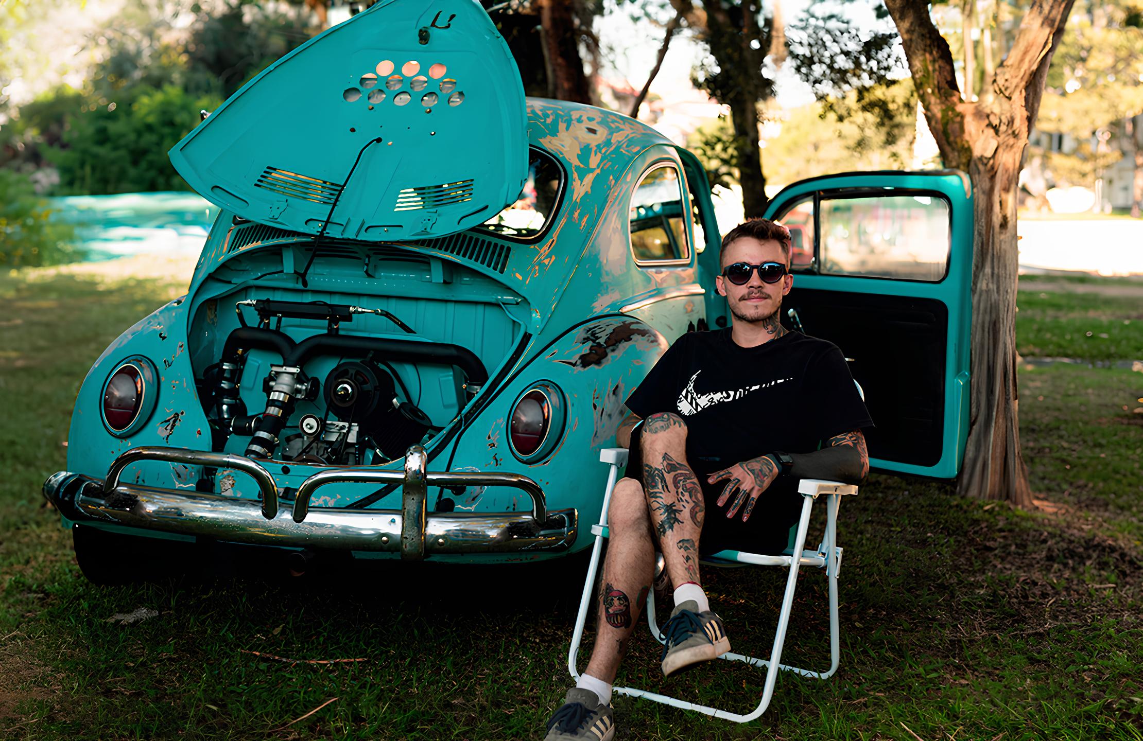 Na foto, Luiz Renato Iurk Neto sentado em uma cadeira de praia ao lado do seu Fusca.