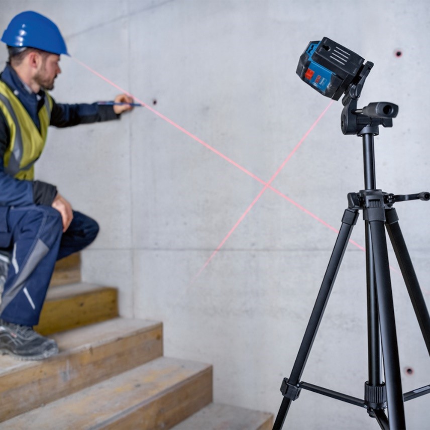 Homem em posição agachado na metade da escada de concreto mostra como usar o nível a laser vermelho gll12-12 bosch com tripé.